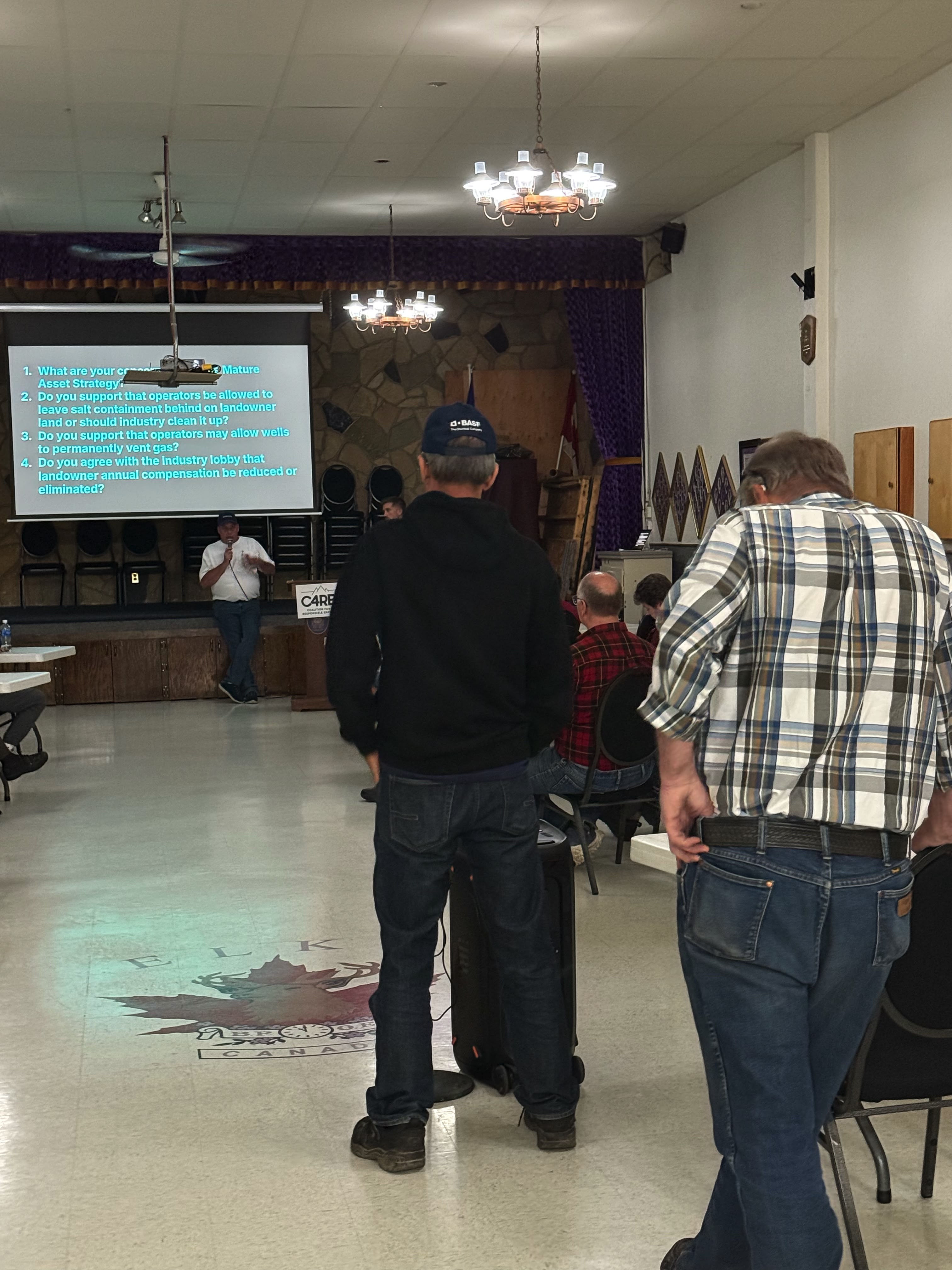 Attendees asking questions and engaging in discussion at the Didsbury town hall, showing active community participation in addressing the oil well cleanup crisis